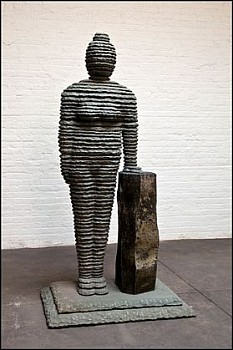 Boaz Vaadia Hulda (#111) (2011), a bronze, bluestone, and basalt figurative sculpture featuring a standing human figure beside a monolithic basalt column, measuring 79 1/2 x 41 x 29 inches. This stacked stone artwork merges ancient techniques with modern